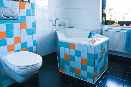 White bathroom, black floor, colorful decorated with tiles in light blue, azure blue and orange - horizontal  