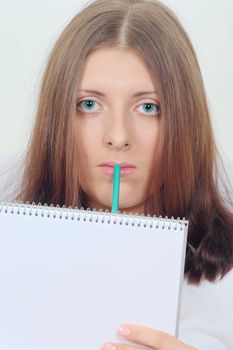 Portrait of the clever girl with a notebook and a pencil removed close up