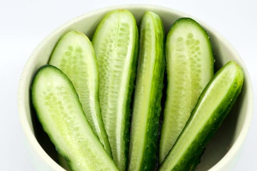 Sliced fresh green cucumber in ceramic dish on white background