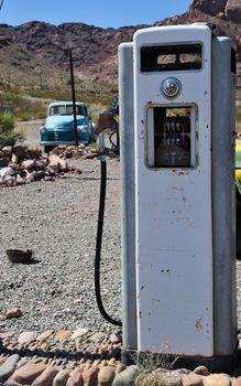 old time vintage gas pump in the middle of no-where with mountain view and a beatup old truck