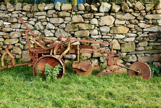 Iron plough abandoned by a dry stone wall