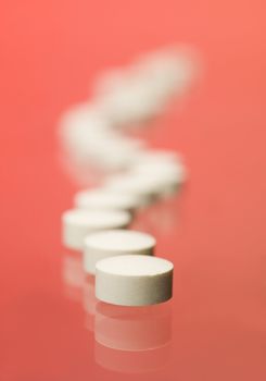 Pills on a row toward red background