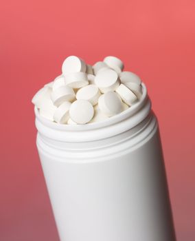 Can with pills towards red background