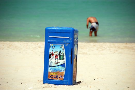 A trashcan and a man bathing in Dubai Sea