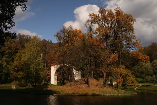 Ruins of ancient arc on small island in autumn park