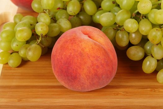 ripe peach with grape rest upon brown table                                     