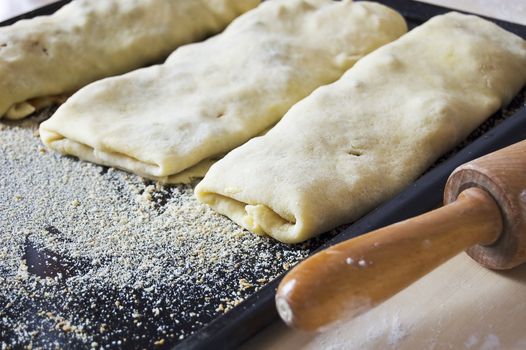 Strudel cakes on baking pan ready to be baked with rolling pin