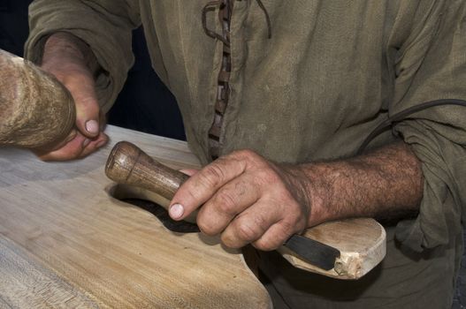 Craftsman hands with tool carving a wood plank