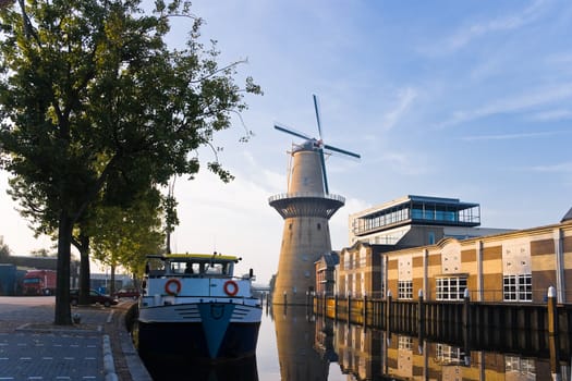 Mill and ship with reflection in water at sunrise - horizontal image