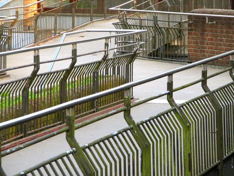 zigzag concrete bridge with railings connecting two buildings