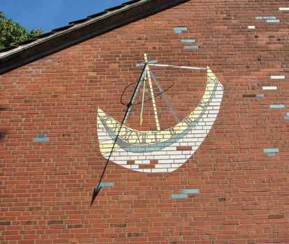 sundial in form of a ship on a brick wall