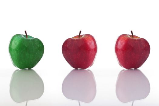 Three apples, one green and two red, isolated on white with reflection. 