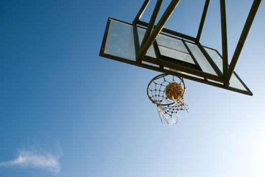 Basketball dropping into the net in a basketball game on an open court at sunset