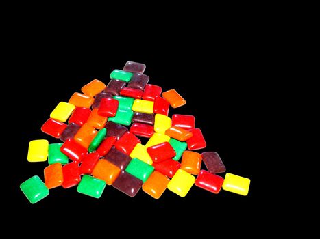 Colored Chewing Gum in a pile isolated on a black background.