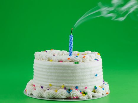 White frosted cake with a candle that has been blown out