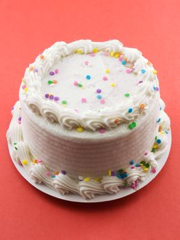 Birthday cake frosted with white frosting on red background