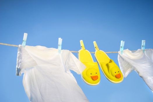 White t-shirts and slippers on the clothesline on a sunny day