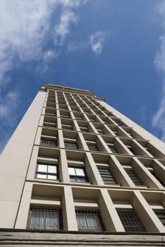 Office building seen from below, with blue sky with some clouds.