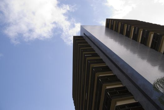 Office building seen from below, with blue sky with some clouds.