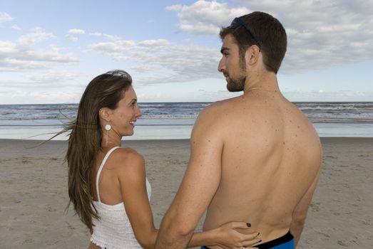 Young healhty couple looking at each other in the beach.