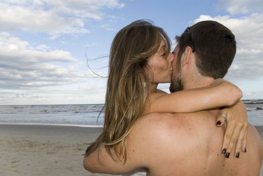 Young healthy couple kissing in the beach. 