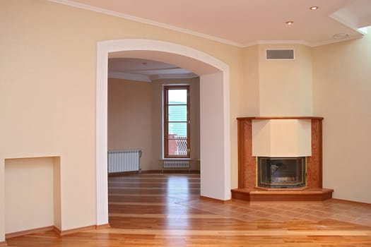 

Empty room with a parquet floor, a portal in the next room, a fireplace and a window
