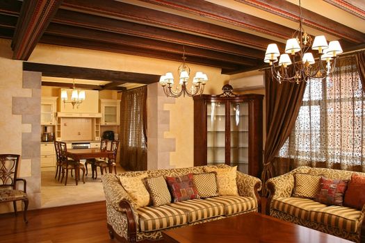 The living room combined with kitchen, with smart furniture, a parquet floor, and a window curtained by portieres
