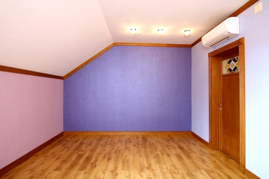 Room without furniture with a parquet floor, blue both pink walls and a wooden door
