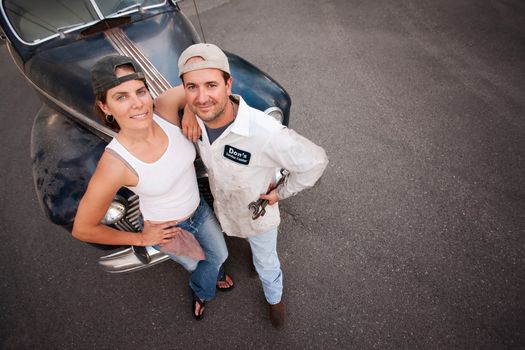 Couple posing with vintage sedan and tools