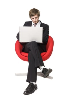 A boy in a red armchair with a laptop