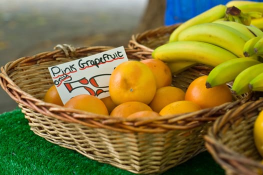 an image showing bananas and pink Grapefruit in display baskets on a market stall 