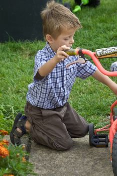 an image of a young boy fixing his first bicycle looking very concerned.