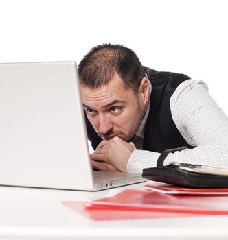 Man behind an office desk studying a laptop