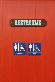 Blue woman man handicapped restroom sign on red wall