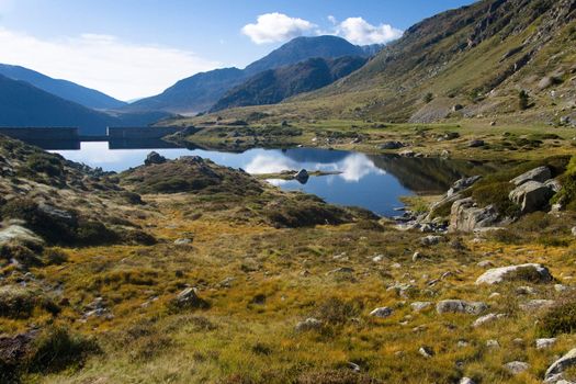 Pyrenees mountain view. Smal mountain lake, in background dam. Summer day. Andora