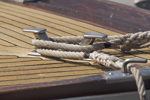 Ropes tied up on a bitt of a wooden boat