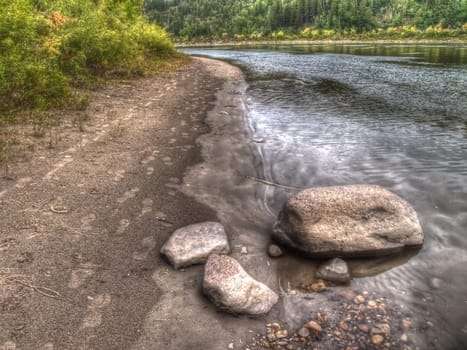 Boulders and footprints on the riverbank in mid summer.