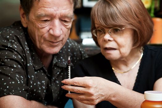 Senior woman and man looking at small hypodermic needle