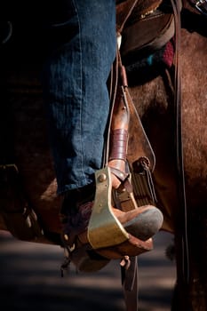 Cowboy leg and foot in stirrup on horse