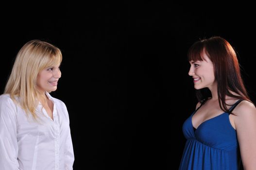 two woman smiling at each other set on a black background