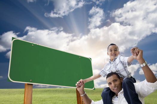 Attractive Happy Hispanic Father and Son in Front of Blank Green Road Sign Ready for Your Own Message.