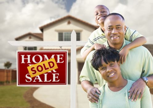 Happy African American Family in Front of New House and Sold Real Estate Sign.