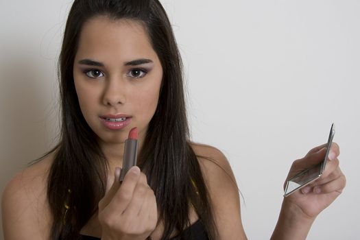 Young woman applying lipstick against a white background