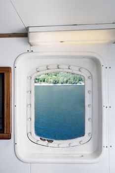 A ship port window looking out on a coast