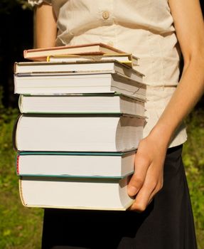 Teen girl holds a stack of books
