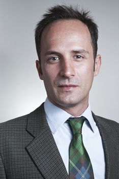 Headshot of white man in a suit with neutral gray background.