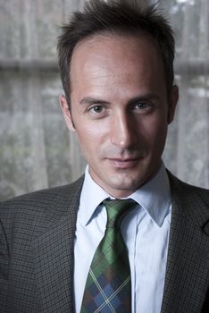 Headshot of white man in a suit with blurred curtain in the background.