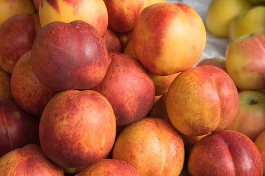 Tiled nectarines on a market stall, with shallow apples on the side.