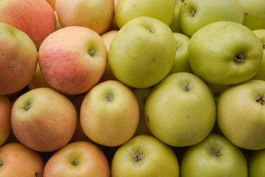 Green and red apples tiled on a market stall.