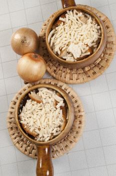 Arrangement of two bowls of onion soup and fresh onions